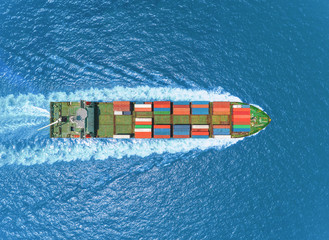 Aerial top view container ship full speed with wonderful wave pattern delivering container for logistics, import export, shipping or transportation.