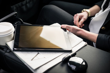 Businesswoman sitting in car touching digital tablet