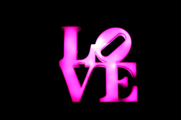 Abstact Plastic pink sign of word LOVE on black background.