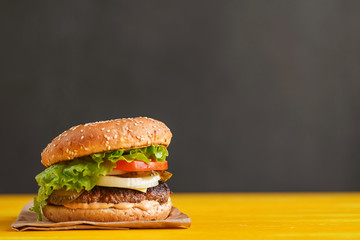 burger on a yellow table and a dark background with space for text