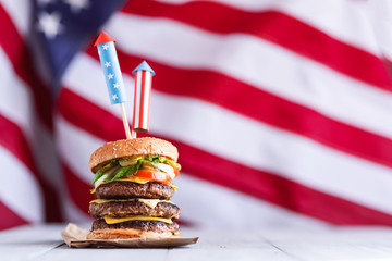 a big burger with three juicy beef patties bonded with American flag firework skewers. burgar...