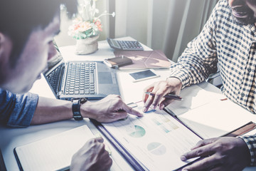 Businessman analyze concept; Young business startup working on market analyst document in graphs and diagramm  on notebook; young coworkers crew working with new startup project