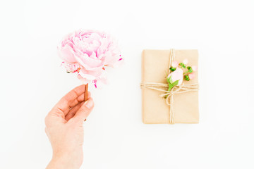 Woman hold peony flower and gift box on white background. Flat lay, top view.