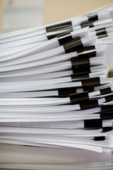 A stack of papers fastened with stationery clips and clips with stickers.