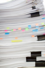 A stack of papers fastened with stationery clips and clips with stickers.