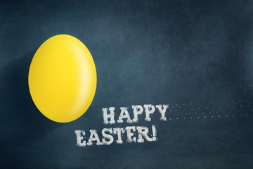 Yellow easter egg on a dark blue background. The inscription in chalk, Happy Easter.Easter background.