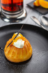 Italian sweet dessert  Baba of Naples with orange liqueur, biscuit cake in a black plate