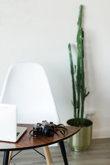 Minimal working place at home with computer, photocamera and cactus
