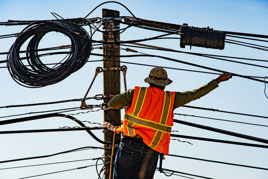 Electrical Lineman on ladder working at utility pole