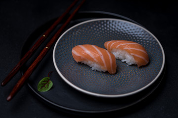 salmon sushi on dark plate with chopsticks and soy sauce