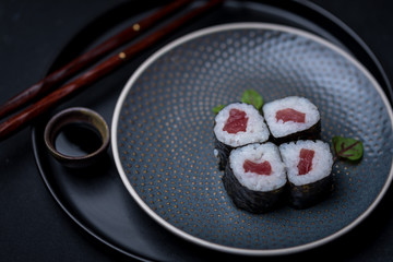 maki sushi raw tuna nori seaweed with soy sauce and chopsticks on a dark plate