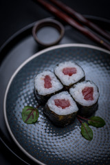 maki sushi raw tuna nori seaweed with soy sauce and chopsticks on a dark plate