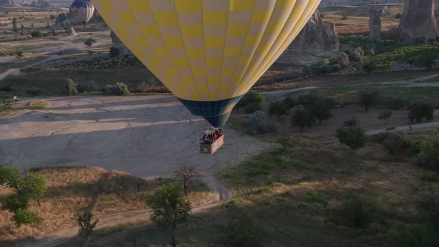 The span of a large yellow balloon, in a basket of people, close-up. Flying over the mountains - Panorama of Cappadocia at sunrise. Wide landscape of the valley of Goreme in Cappadocia. 4k. Aerial pho