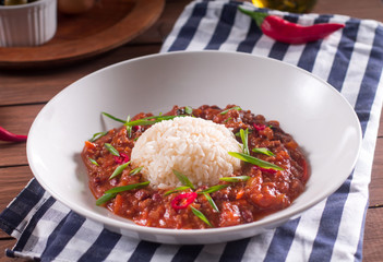 Chili con carne in a white plate. Cooked with ground beef, tomatoes, pepper, beans, garlic, onion, cilantro