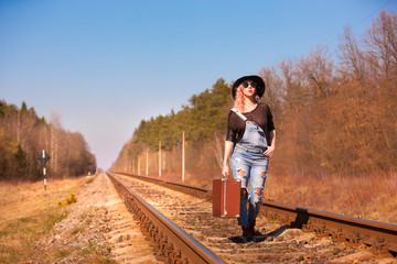 Traveling woman walking on railroad tracks with a suitcase