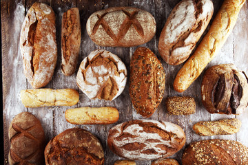 Different kinds of bread and bread rolls on board from above. Kitchen or bakery