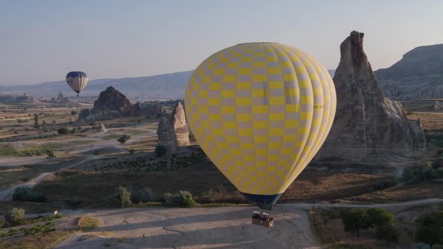 The span of a large yellow balloon, in a basket of people, close-up. Flying over the mountains - Panorama of Cappadocia at sunrise. Wide landscape of the valley of Goreme in Cappadocia. 4k. Aerial pho