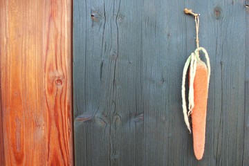 Möhre aus Filz vor dunkelgrüner Holzwand, Ostermotiv