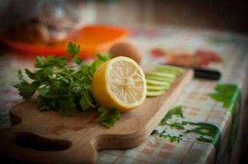 Parsley, lemon, egg and slices of zucchini on wooden board.