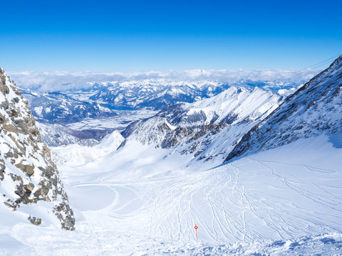 Winter landscape with free ride piste and view on snow covered slopes and blue sky, with Aerial view of Zell am See lake from the top of Kitzsteinhorn mountain on . Kaprun ski resort, National Park