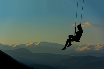 silhouette - young girl swinging in the sunset