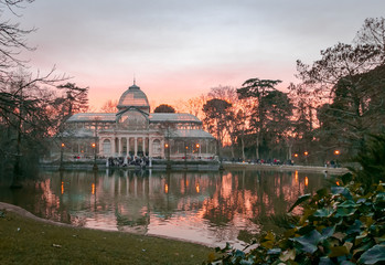 Fototapeta na wymiar The Palacio de Cristal at sunset (Crystal Palace) is a glass and metal structure located in Madrid's Buen Retiro Park
