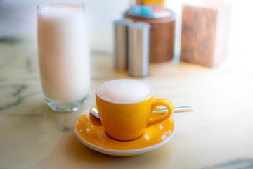 A coffee cup on the breakfast table with milk cup in the cafe
