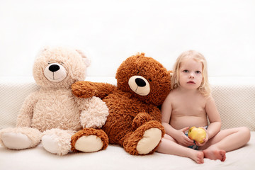 Little boy, three years old, plays and eats an apple on the sofa.