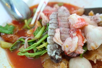 Yentafo Spicy noodle soup,hot and spicy ,with mix seafood, crayfish, shrimp. Asian spicy seafood noodle soup in white bowl on table background. Thai style noodle and street food of Thailand.