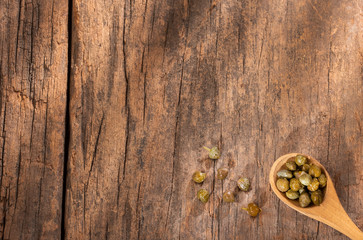 Fototapeta na wymiar Capers in wooden spoon - Capparis spinosa. Wood background