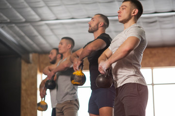 Group of Fit and Focused Men Training With Kettlebells.