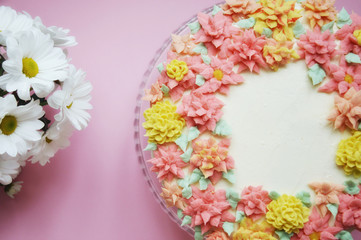 cake with cream flowers on pink background