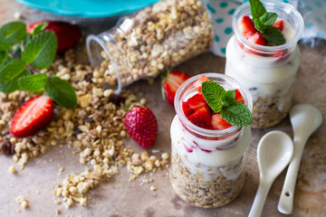 Homemade summer healthy breakfast. Greek yogurt with granola, pieces fresh strawberry on stone table.