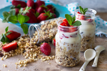 Homemade summer healthy breakfast. Greek yogurt with granola, pieces fresh strawberry on stone table.