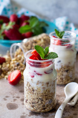 Homemade summer healthy breakfast. Greek yogurt with granola, pieces fresh strawberry on stone table.