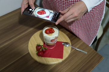 layered dessert or Magnolia with strawberries, biscuit cake and cream cheese on a white wood background.