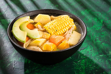 Colombian cuisine: ajiaco soup with chicken and vegetables close up in a bowl.