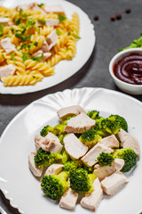fusilli pasta with chicken breast and broccoli with chicken breast in white plate on Dark grey black slate background