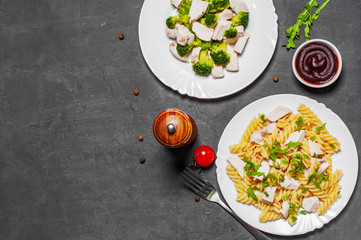 fusilli pasta with chicken breast and broccoli with chicken breast in white plate on Dark grey black slate background