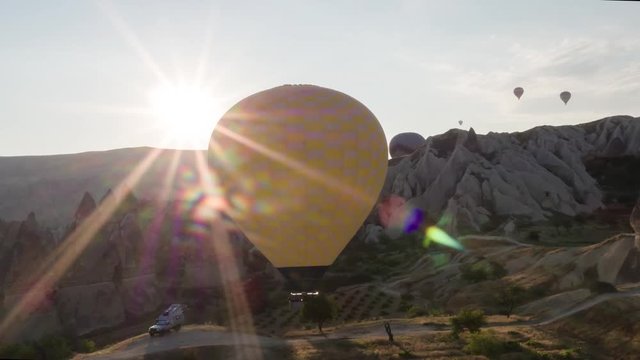 The span of a large yellow balloon, in a basket of people, close-up. Flying over the mountains - Panorama of Cappadocia through the sun's rays. Wide landscape of the valley of Goreme in Cappadocia. 4k