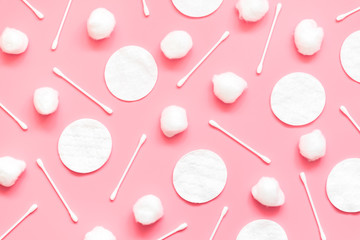 Hygienic background made from cotton balls, pads and swabs on a pink background.
