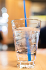 Glass of water with ice cubes on wooden table at restaurant. 