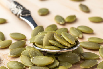 Pumpkin seeds in a dessertspoon on a wooden table