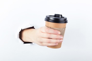 Female hand out of the hole in the paperman, keeps a brown glass of coffee with him. Isolate on white background.