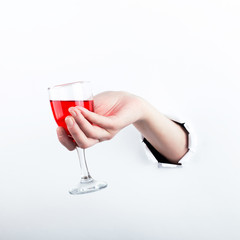 Female hand out of the hole in the paperman, holding a glass of red wine. Isolate on white background.