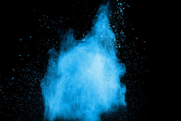 Abstract blue dust explosion on black background. Freeze motion of blue powder splash. Painted Holi in festival.