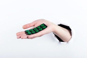 Female hand out of the hole in the paperman, holding blisters with pills. Isolate on white background.