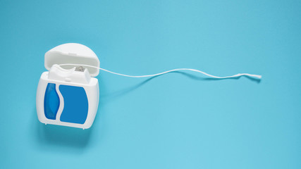 Dental floss on blue background. Dental health care and oral hygiene concept. Copy space.
