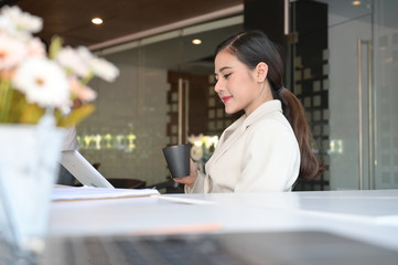Asian businesswoman working with clip board and coffee on hands.