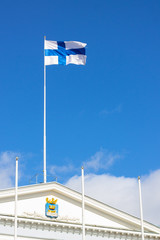 Finnish flag waves against the sky above the Helsinki City Hall